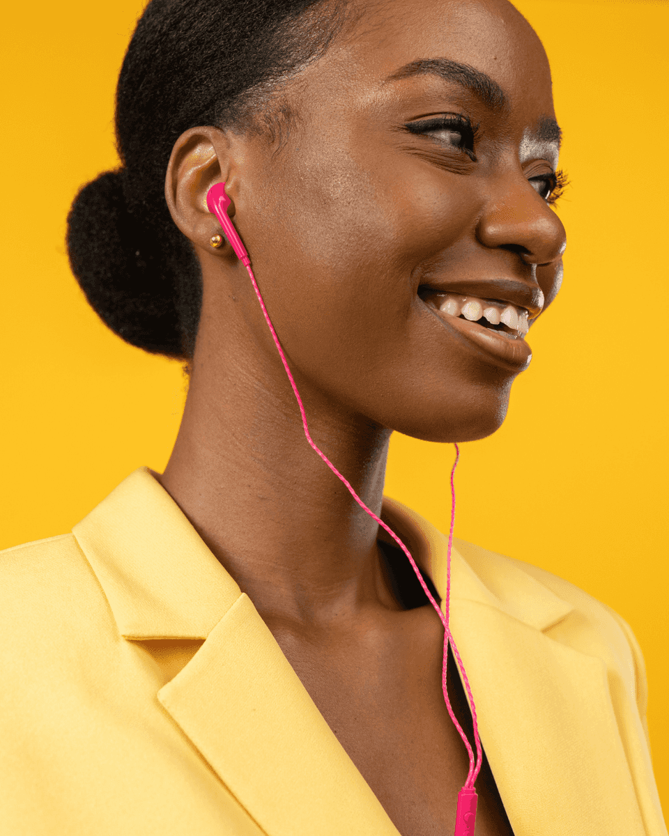 Woman with pink earbuds in a yellow blazer