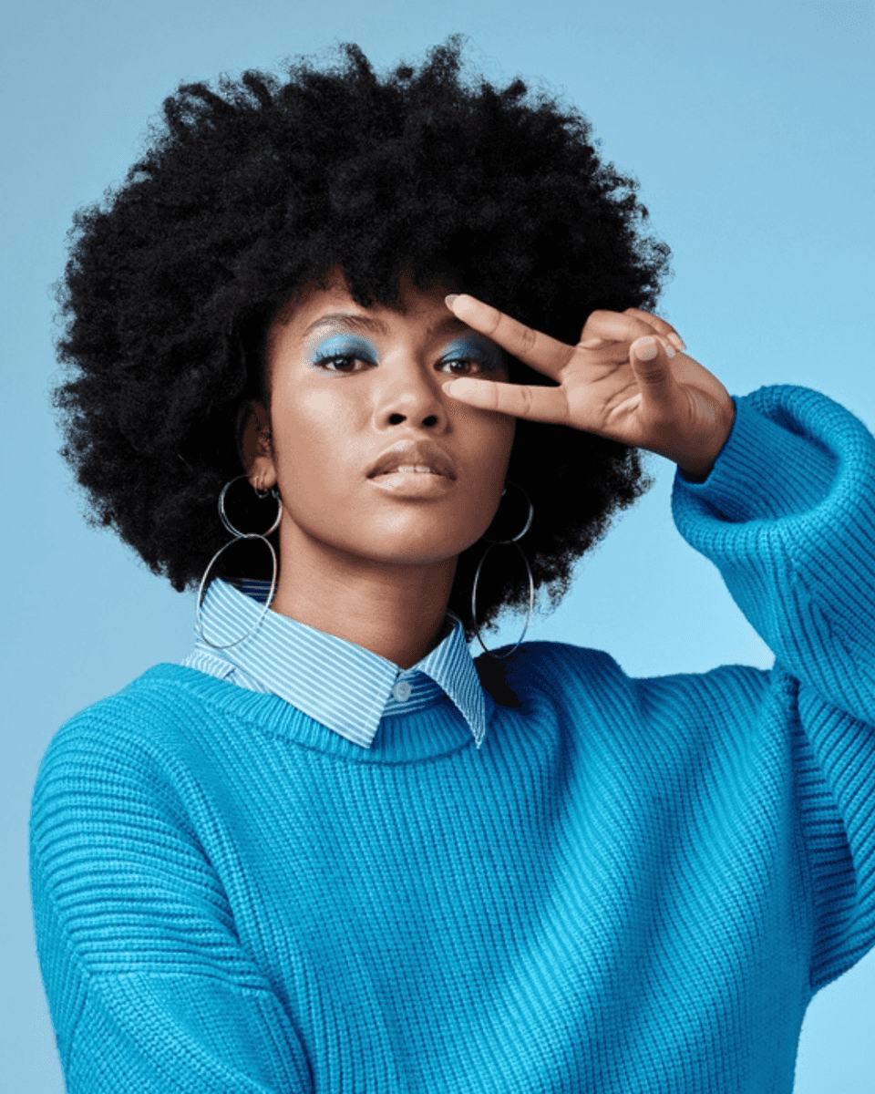 Woman in a teal sweater making a peace sign